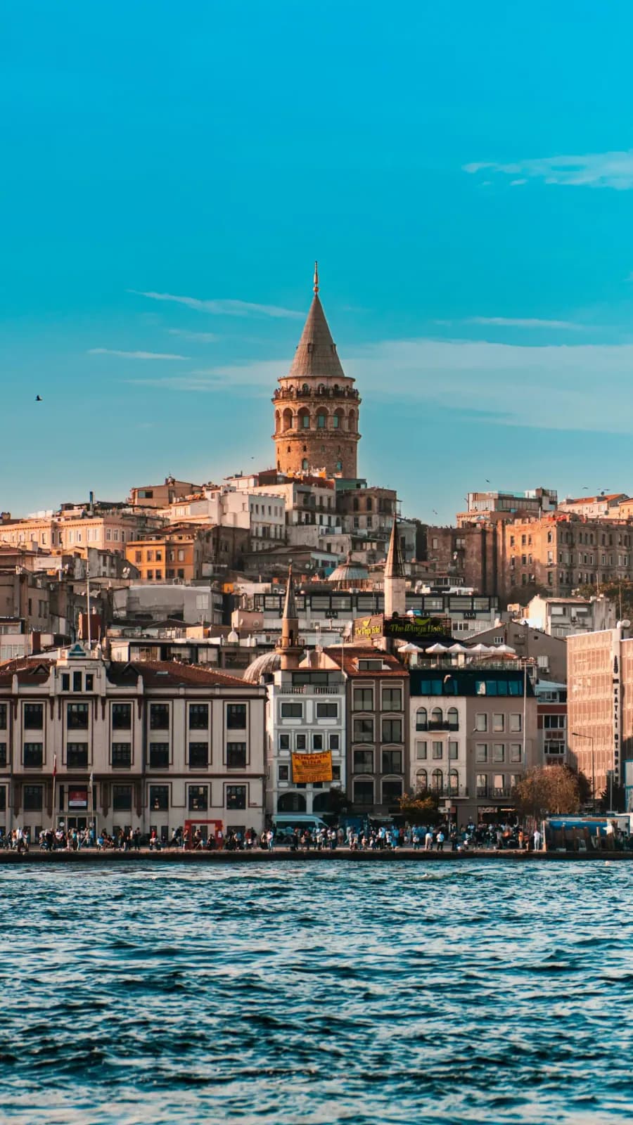 Looking up at the massive cylindrical body of Galata Tower from the streets of Karakoy.