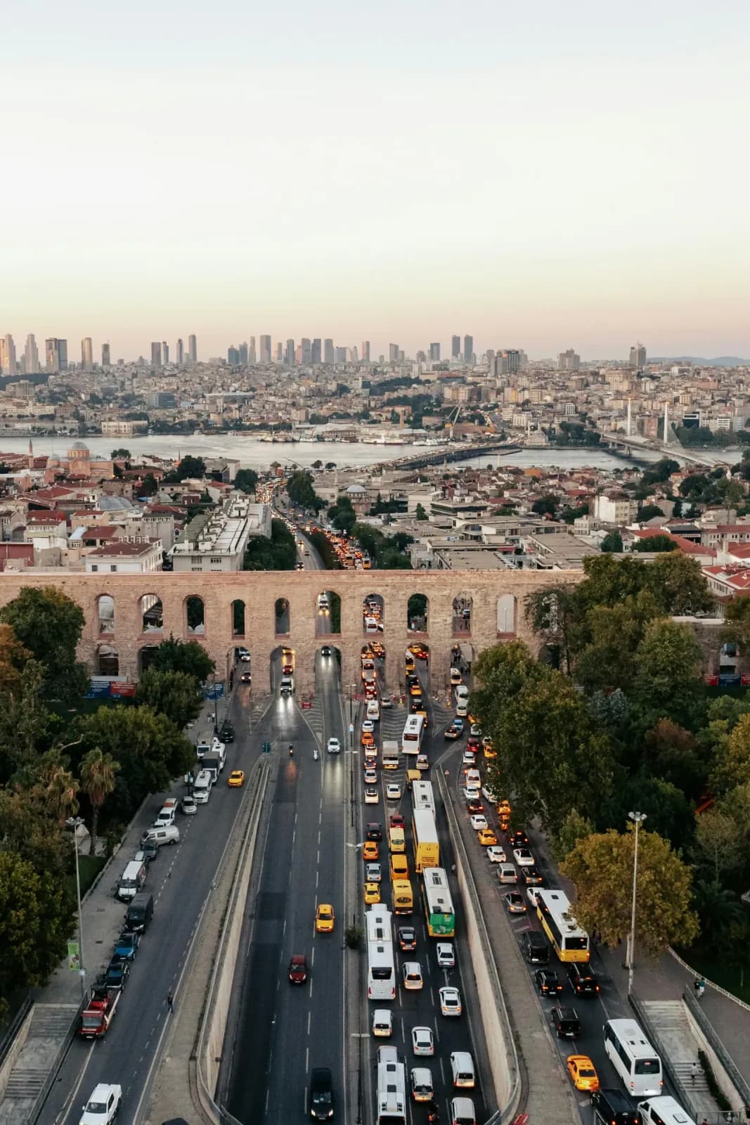Sunset view of the Valens Aqueduct silhouette against the modern Istanbul city lights.