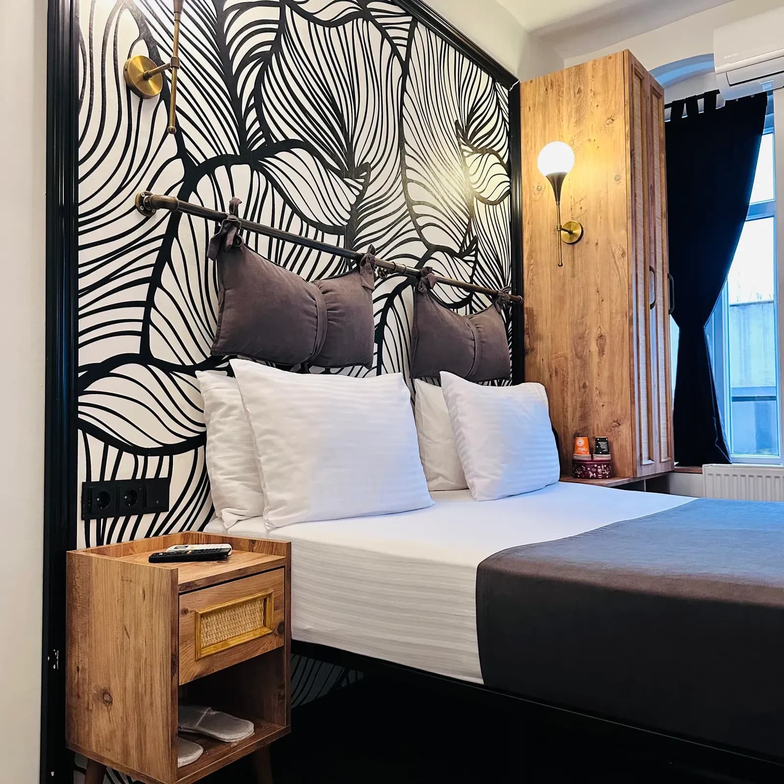 Striped pillows and grey bolsters against a leaf-patterned wall in a Design Room, Istanbul