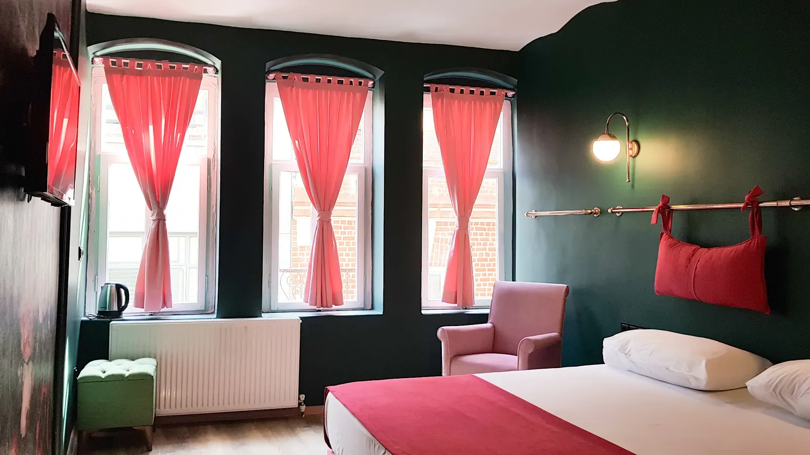 Coral curtains and a brass lamp beside the bed in a green-walled Design Suite, Karaköy, Istanbul